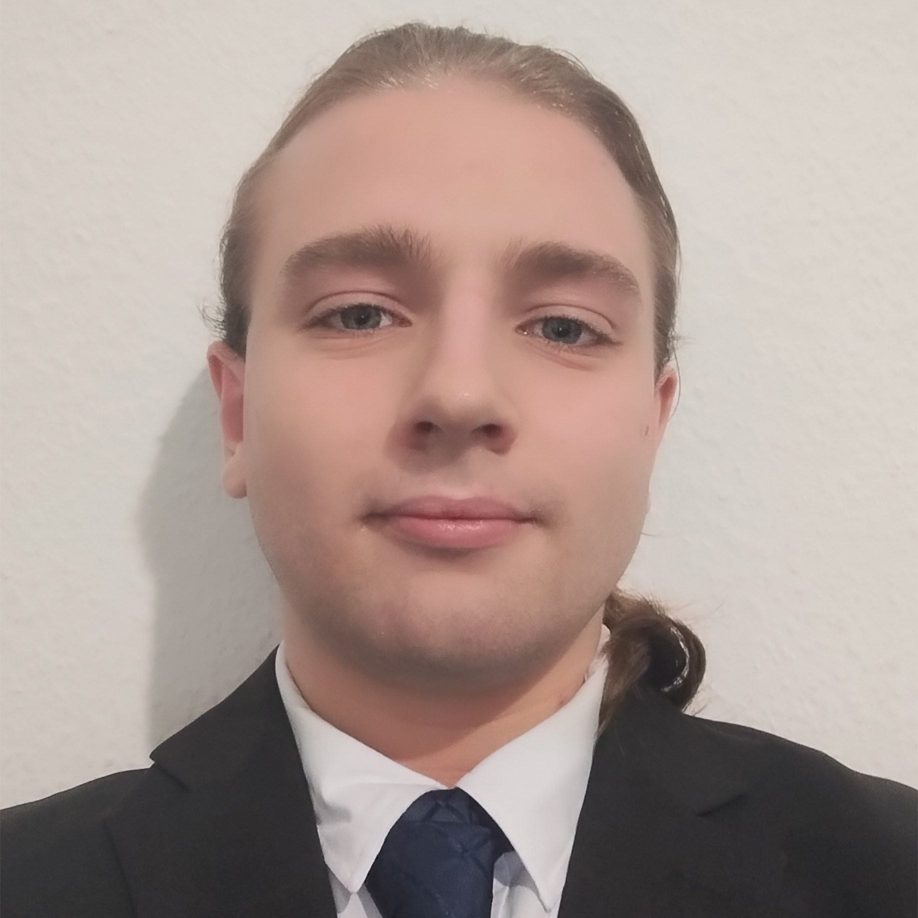 A photo of Seth Maxwell in a black suit against a plain white background